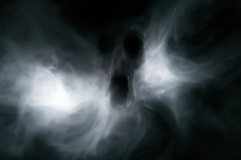Ghostly screaming face emerging from swirling white smoke in dark atmosphere