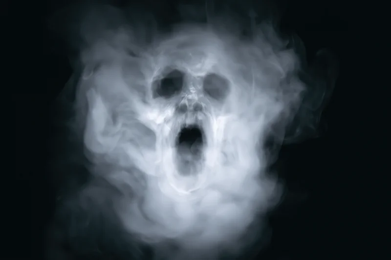 Ghostly screaming face emerging from swirling white smoke against black background