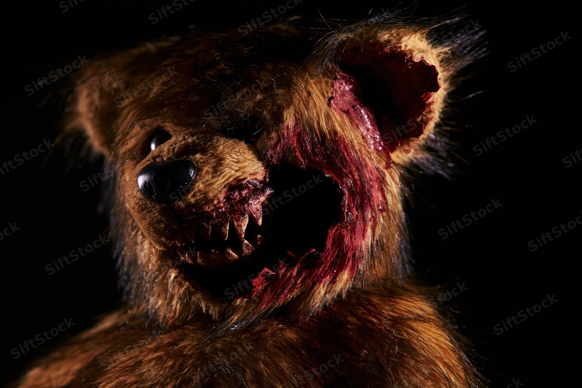 Horror-themed teddy bear with torn mouth and blood on dark background
