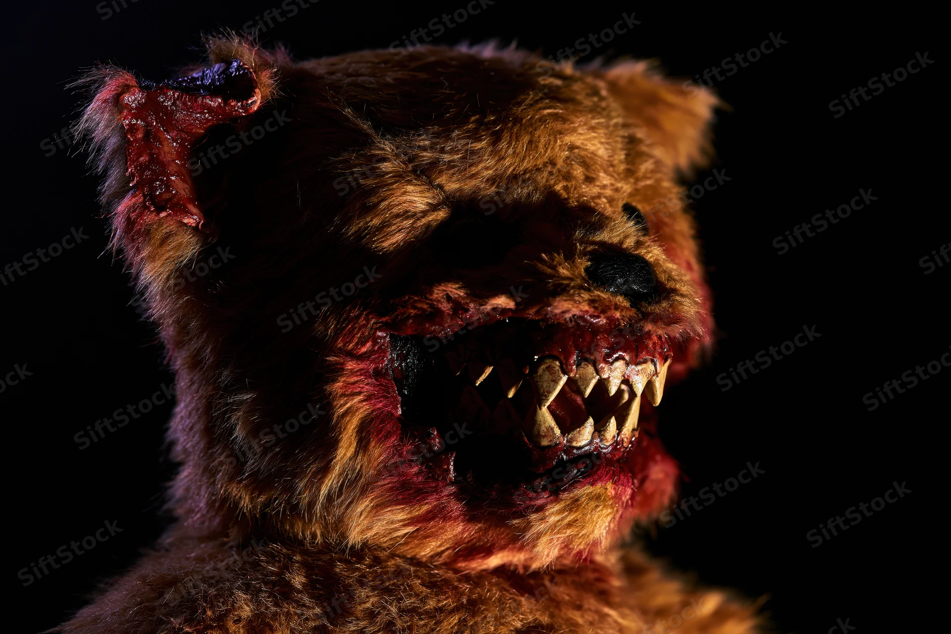 Horror-themed teddy bear with torn mouth and fangs against dark background