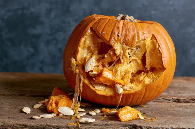 Smashed pumpkin with exposed seeds and pulp on a wooden table
