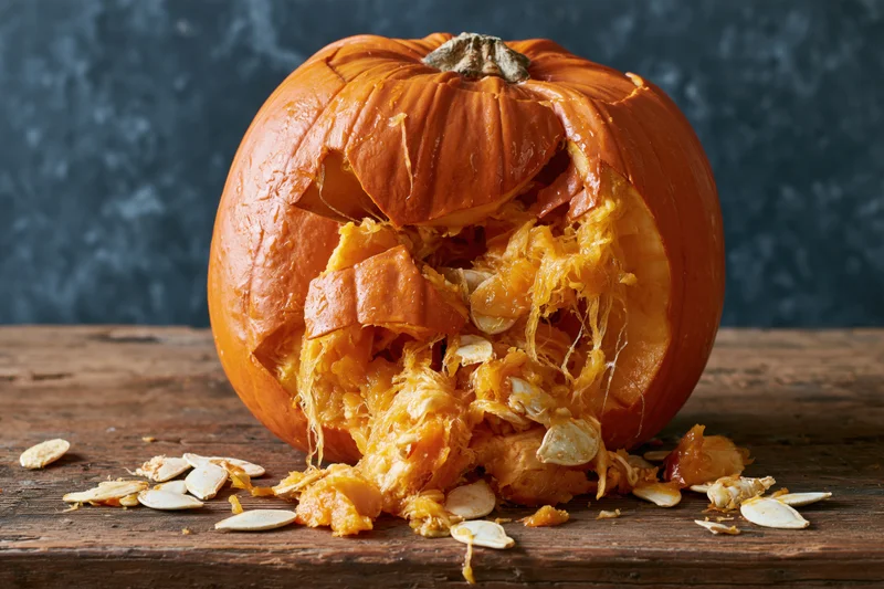 Broken pumpkin with exposed seeds and pulp on a wooden table