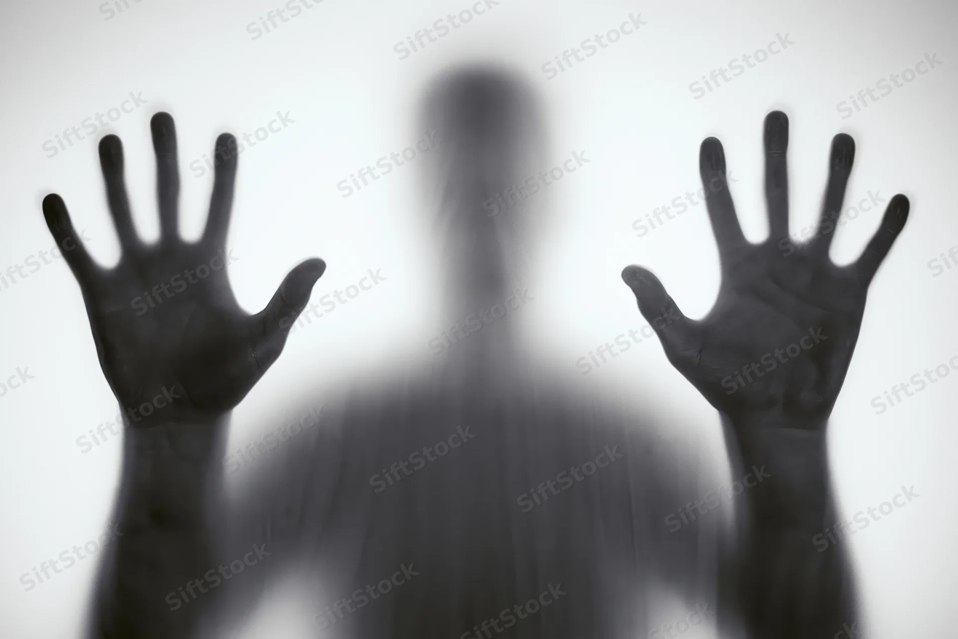 Blurred silhouette of a person pressing hands against frosted glass