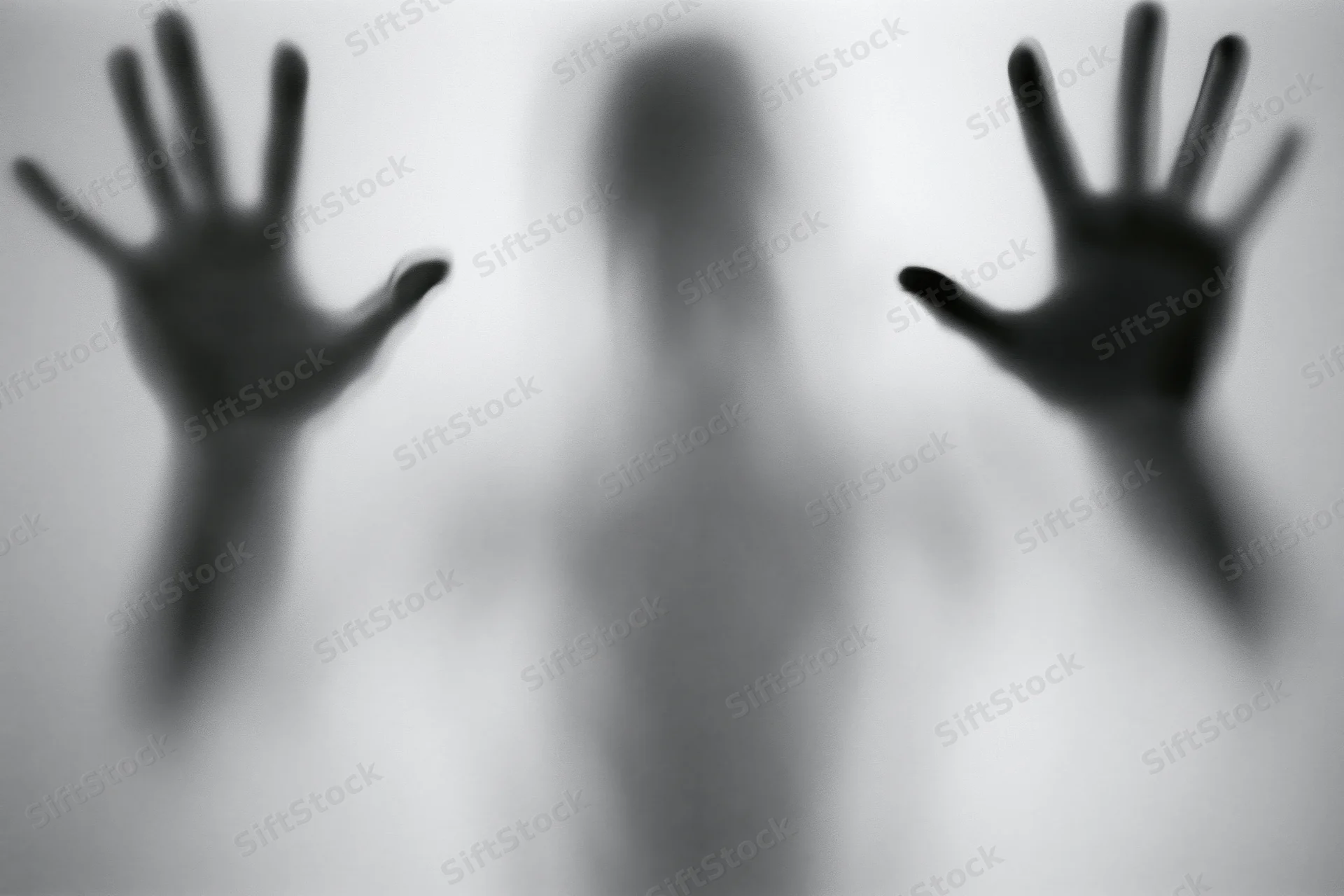 Silhouette of a person pressing hands against frosted glass