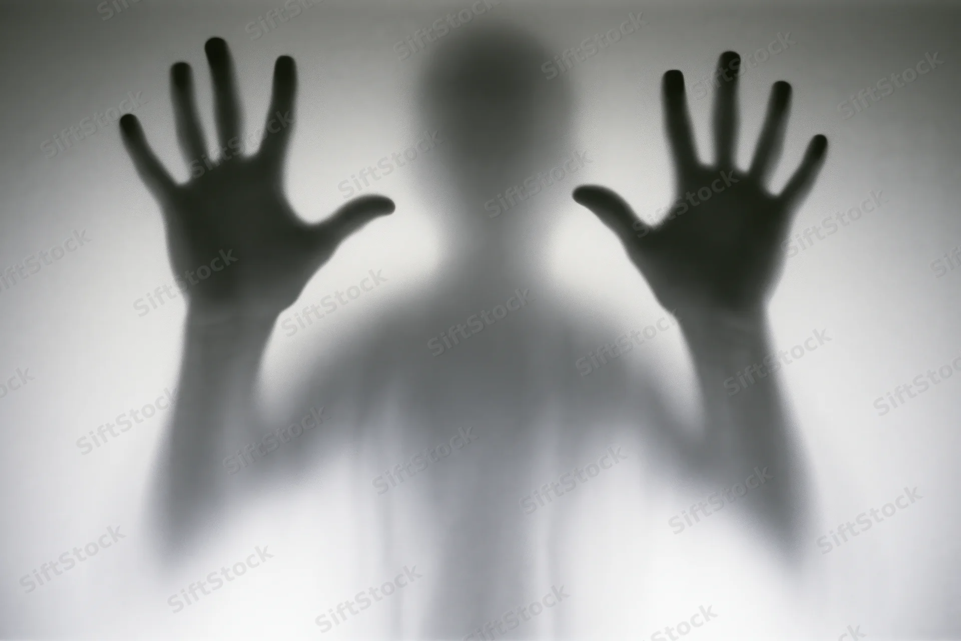 Blurred silhouette of a person pressing hands against frosted glass