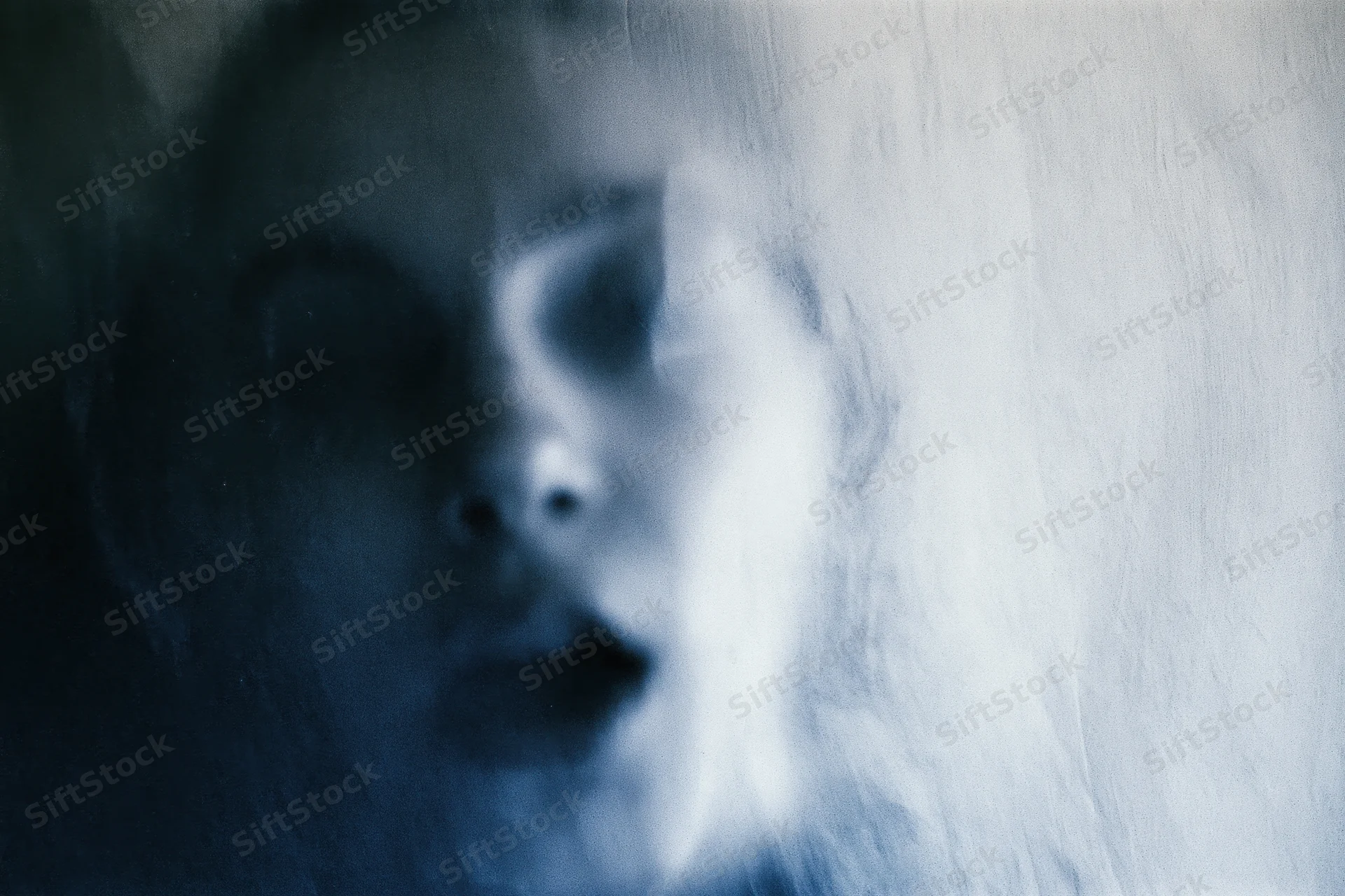 Woman's face pressed against frosted glass with blurred features and blue lighting