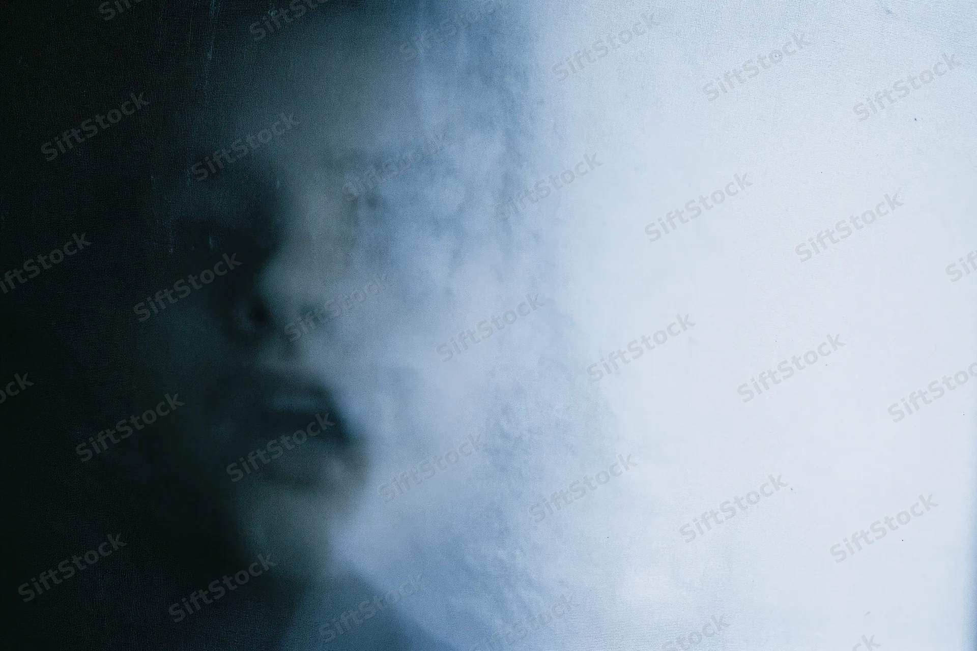 Blurred face pressed against frosted glass in dim indoor light