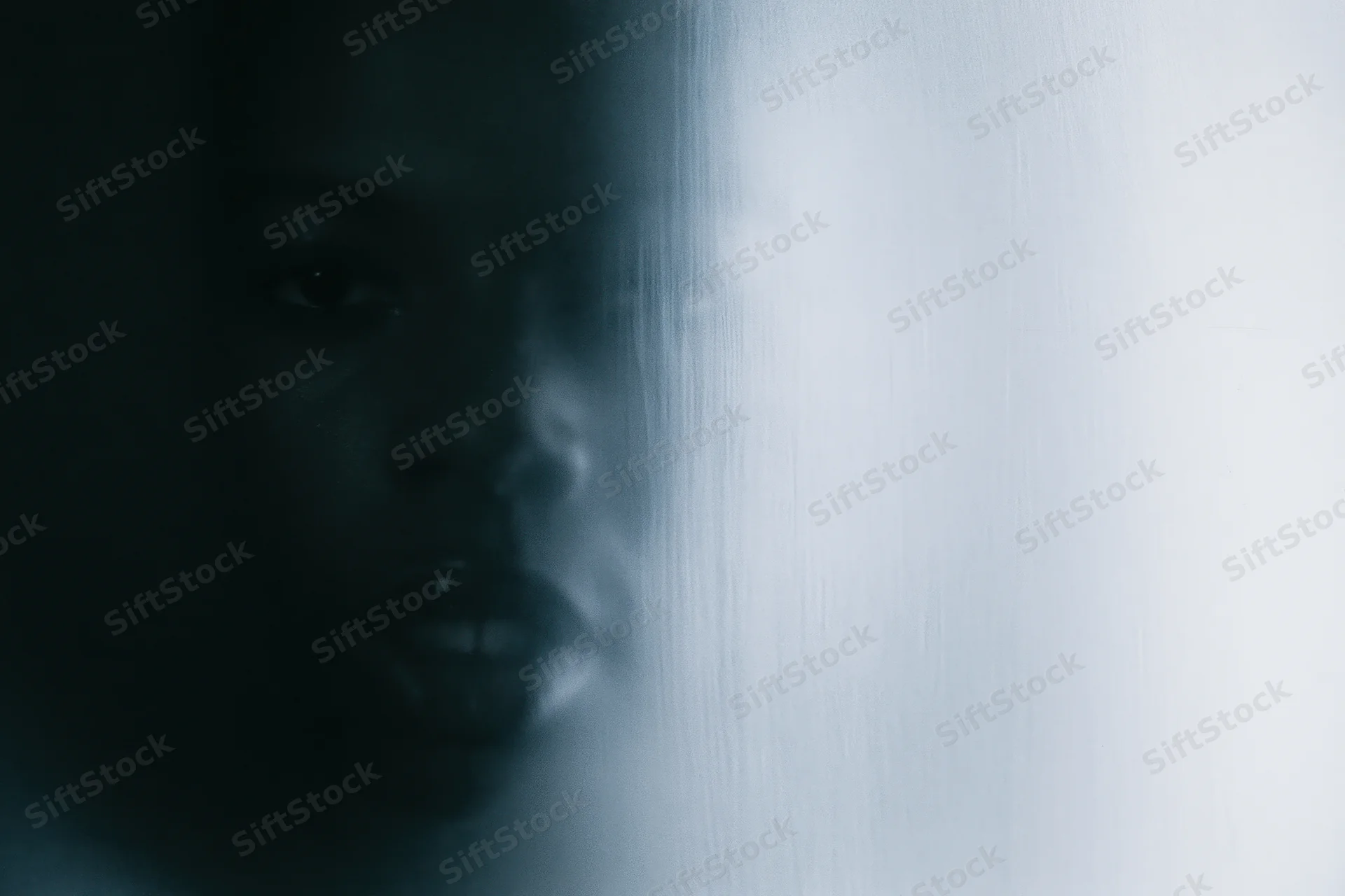 Woman pressing face against frosted glass in dim light