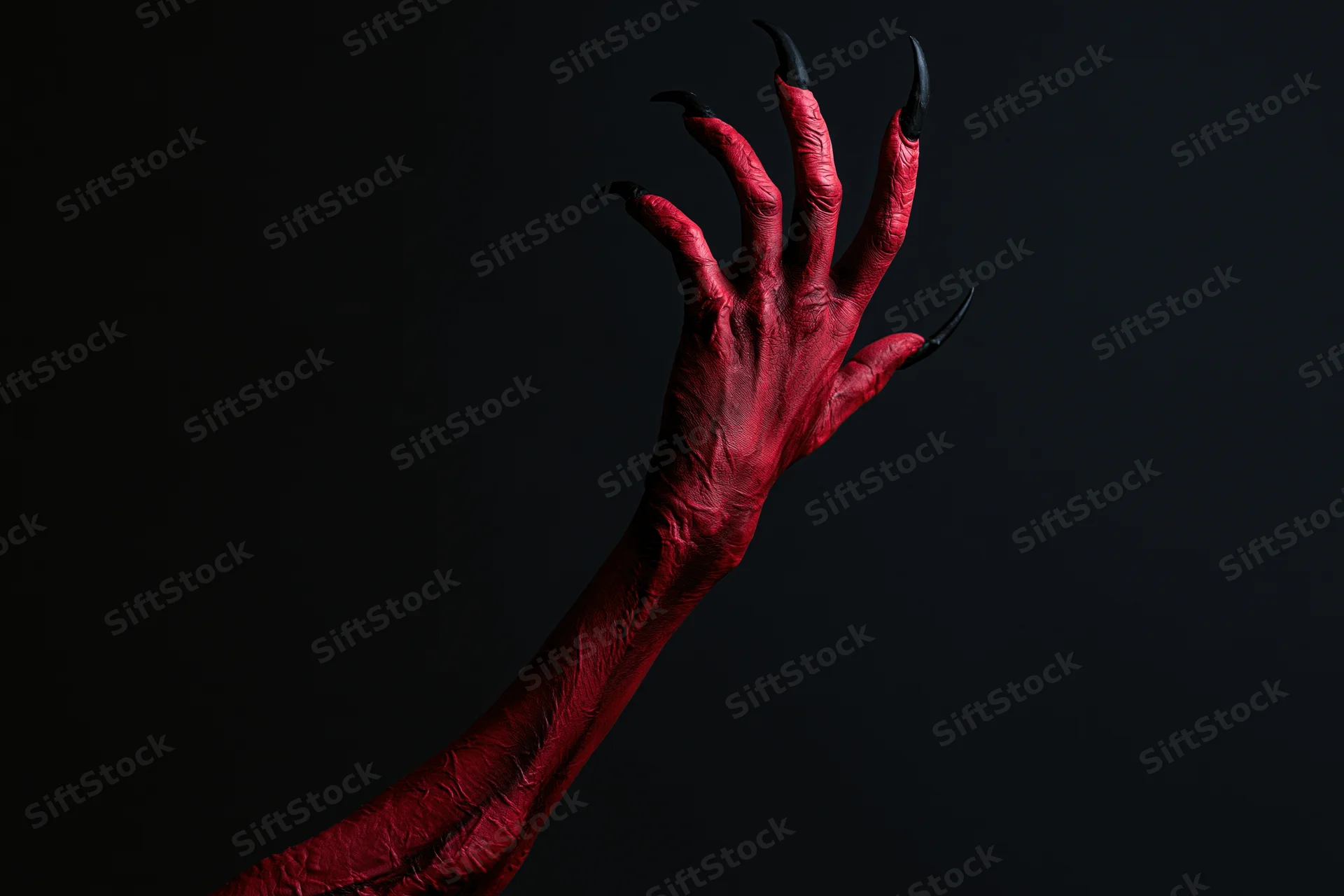 Red demon hand with black claws reaching upward against dark background