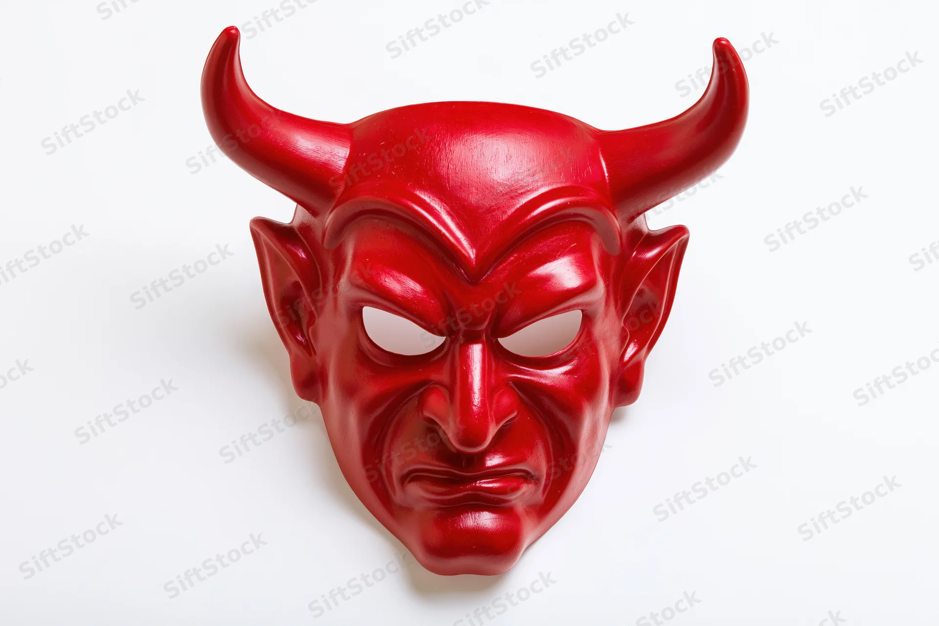 Red devil mask with curved horns and menacing expression on white background