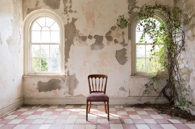 Wooden chair with faded purple seat in an abandoned room with peeling walls and checkered tile floor