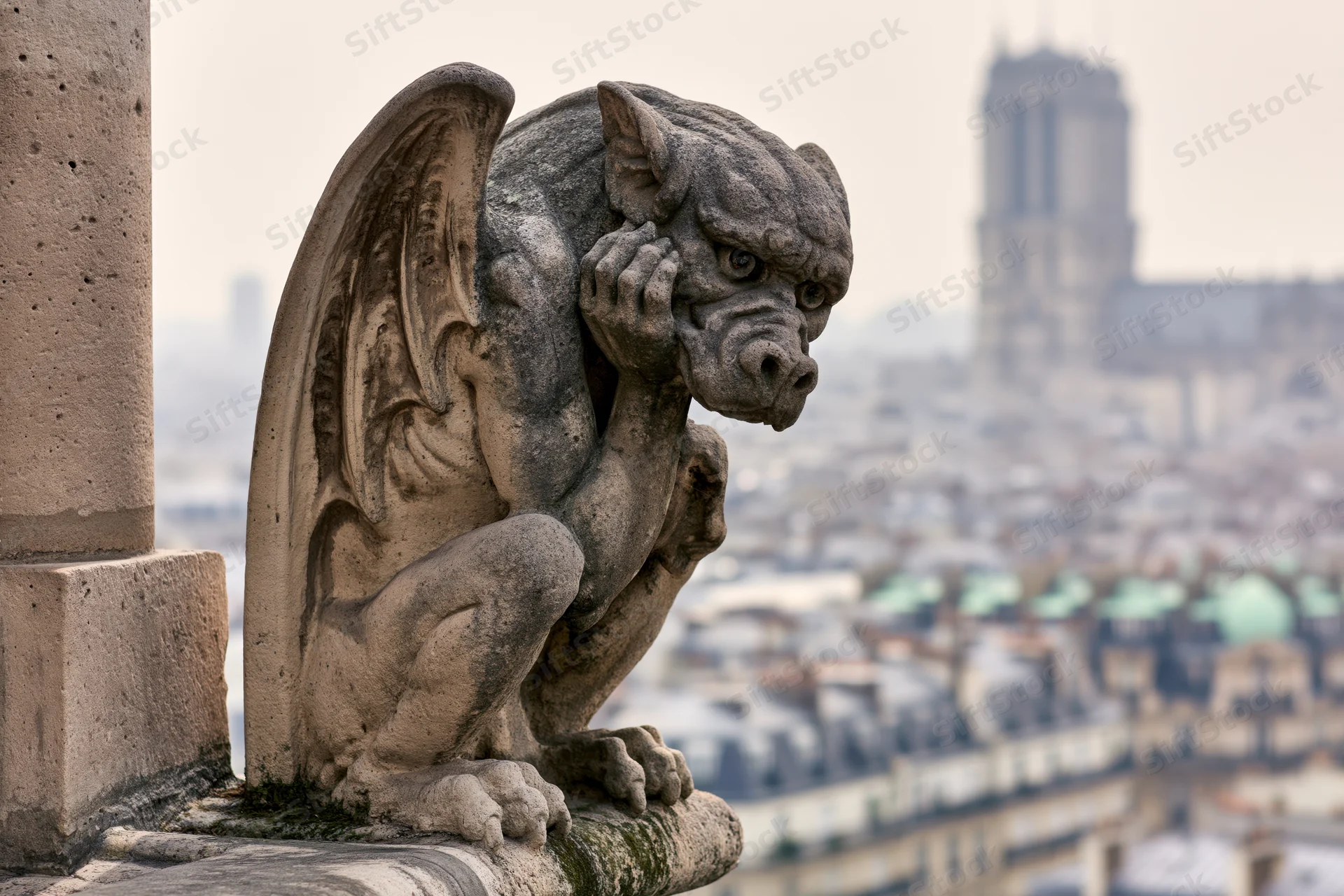 Stone gargoyle sculpture perched on cathedral ledge overlooking paris cityscape