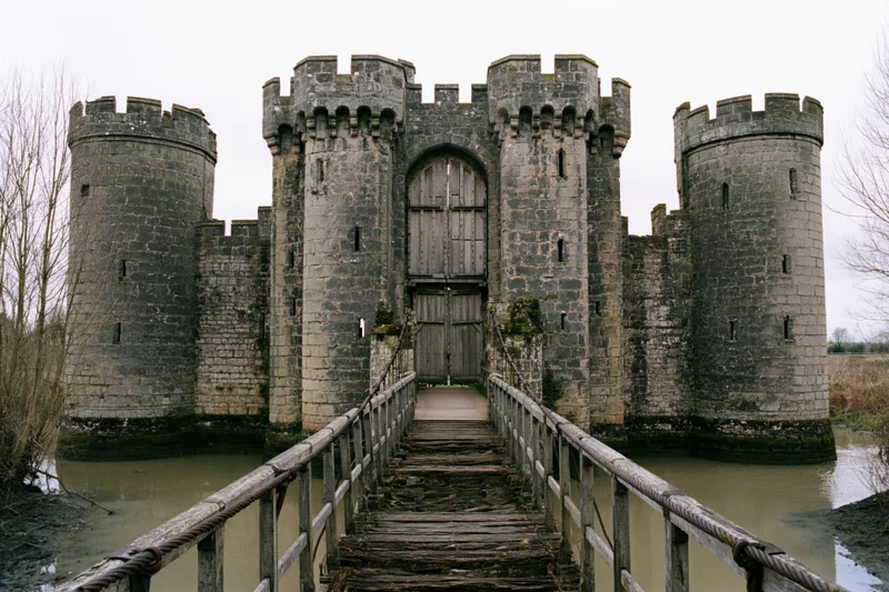 Stone castle with crenellated towers and wooden bridge over moat
