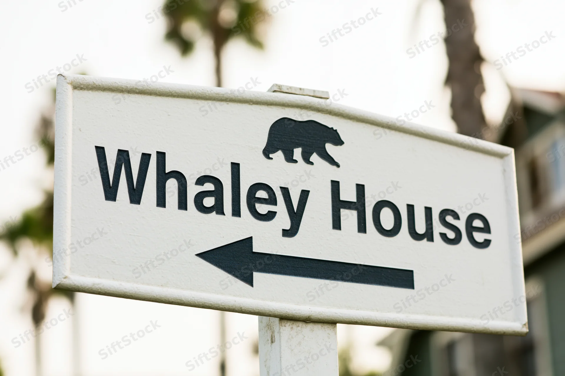 White directional sign for Whaley House with bear symbol and left arrow pointing toward the landmark in San Diego