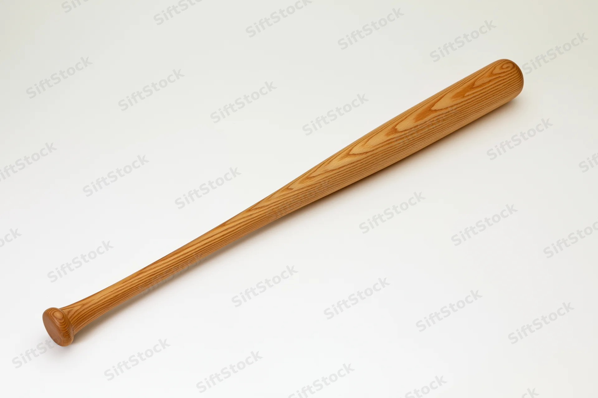 Wooden baseball bat lying diagonally on plain white studio background