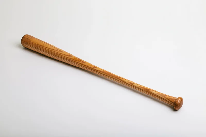 Wooden baseball bat lying diagonally on plain white studio background