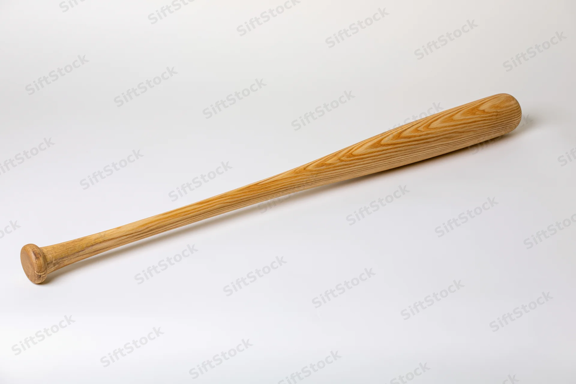 Wooden baseball bat lying diagonally on plain white studio background
