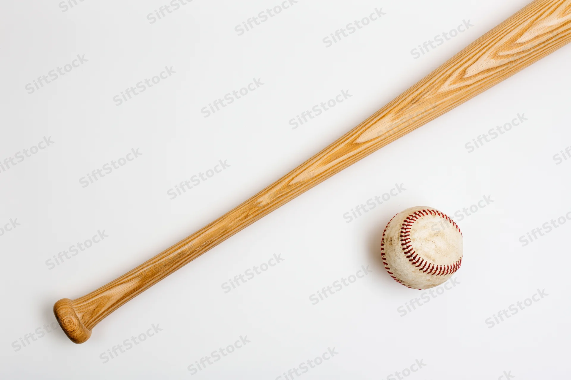 Wooden baseball bat and baseball resting diagonally on white surface