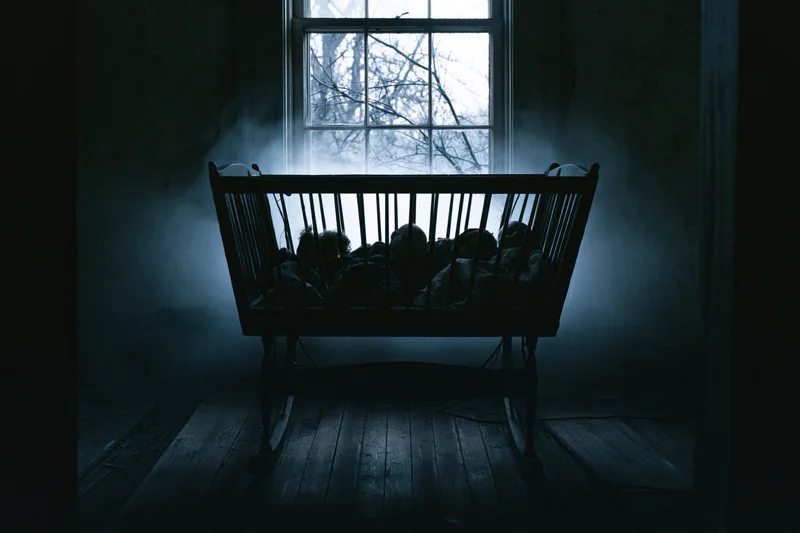 Antique wooden baby cradle in dark abandoned room with fog near window