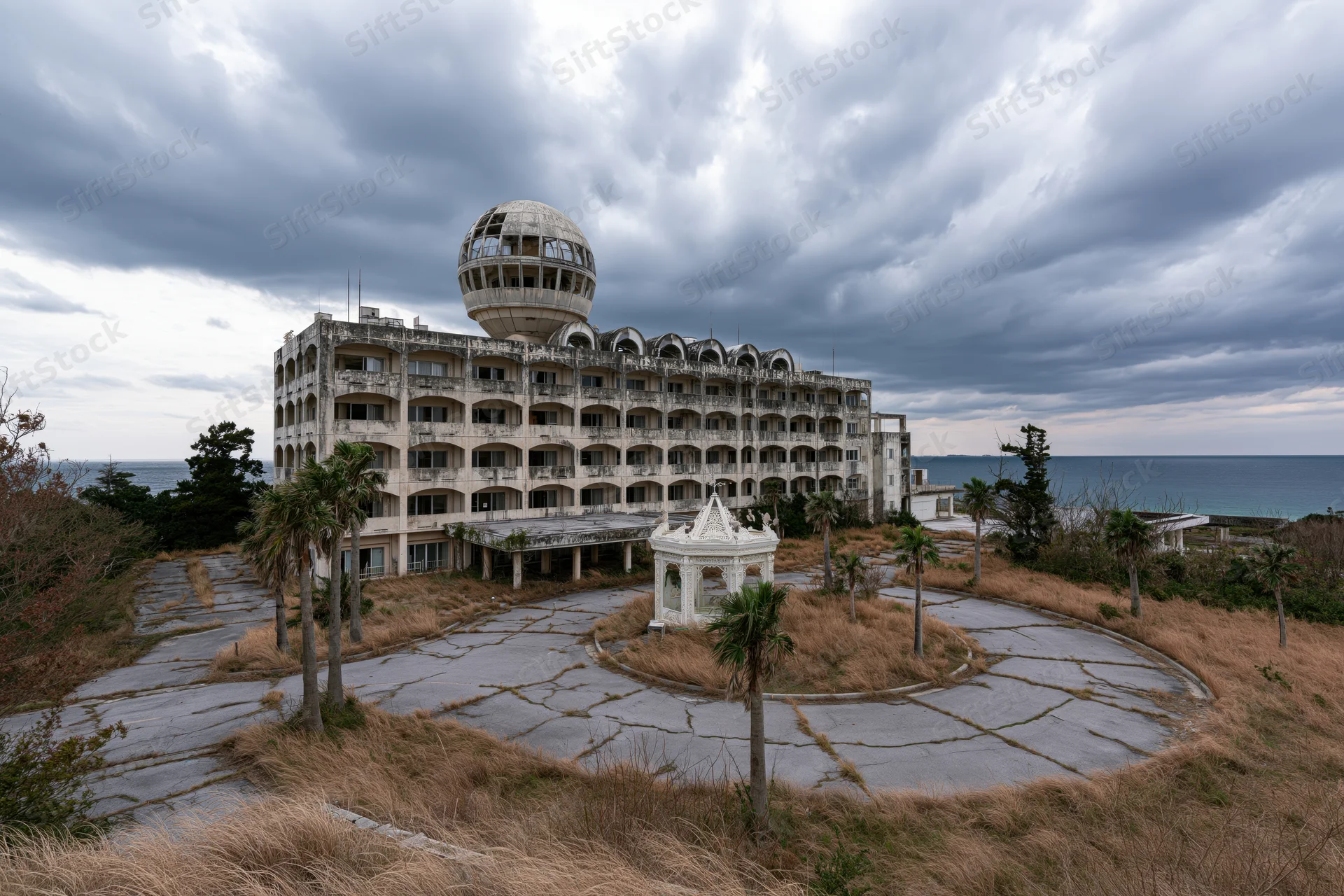 Abandoned japanese resort hotel with weathered concrete facade and circular dome overlooking the ocean