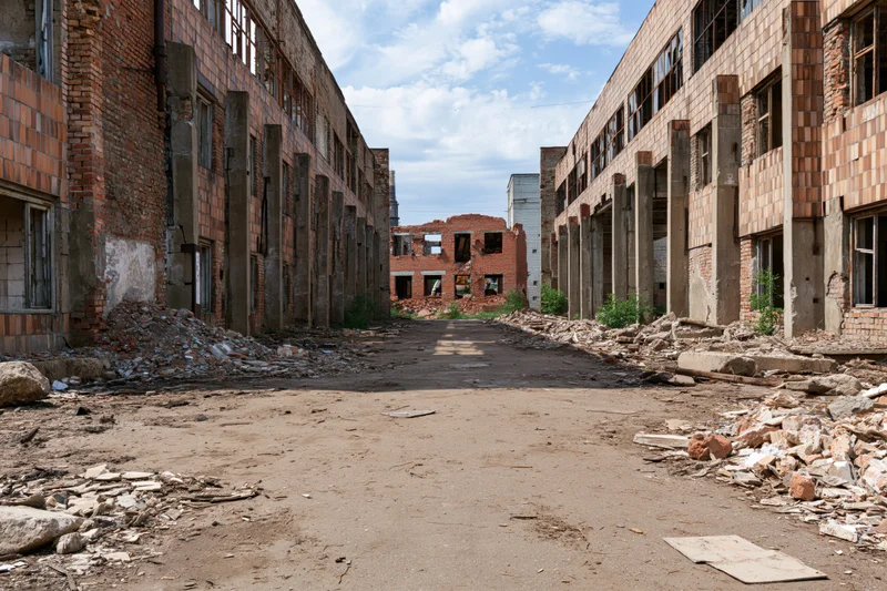 Symmetrical dirt courtyard between ruined brick buildings in abandoned soviet-era industrial complex