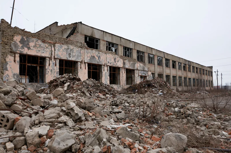 Abandoned soviet-era industrial factory building with collapsed walls and rubble in foreground