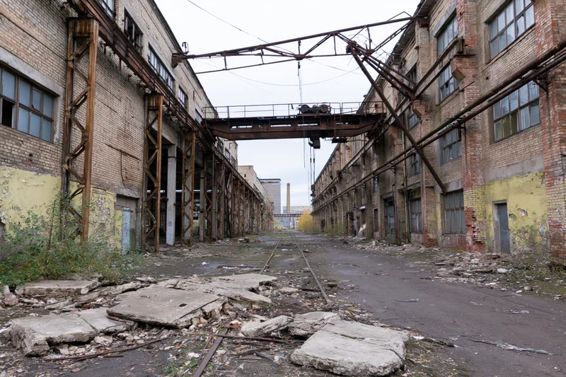 Abandoned soviet-era industrial factory complex with rusted overhead crane and broken concrete floor