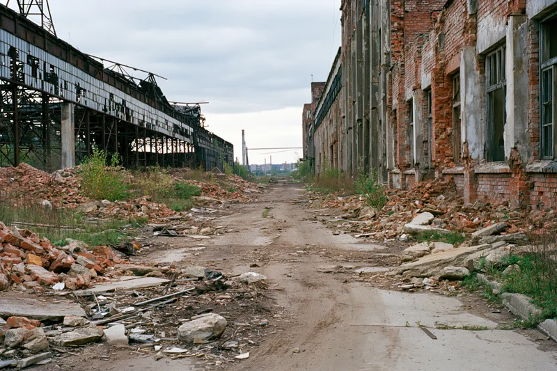 Symmetrical corridor through abandoned soviet industrial complex with rubble and overgrown vegetation