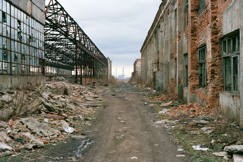 Symmetrical corridor through abandoned soviet industrial complex with crumbling brick buildings and rubble on either side
