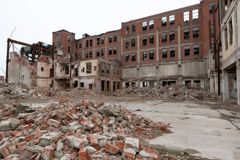 Abandoned industrial factory complex mid-demolition with rubble and broken walls