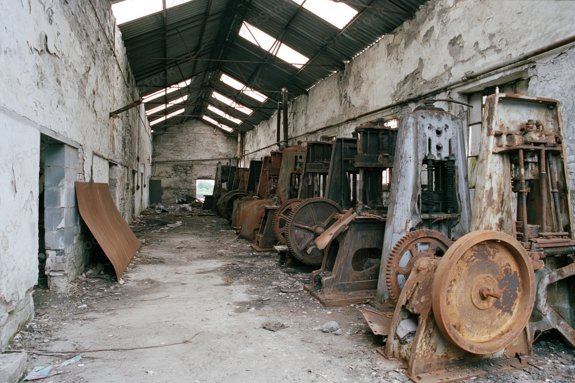 Rows of rusted industrial machinery inside an abandoned factory interior