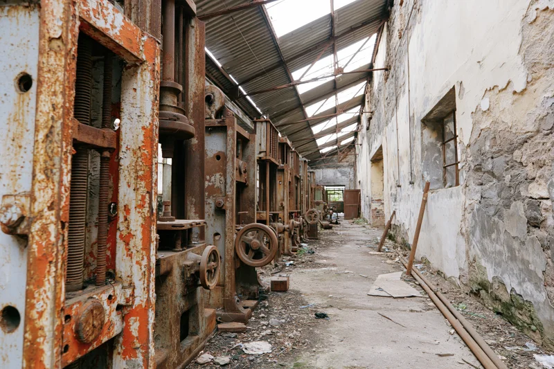 Rows of rusted industrial machinery in an abandoned factory interior