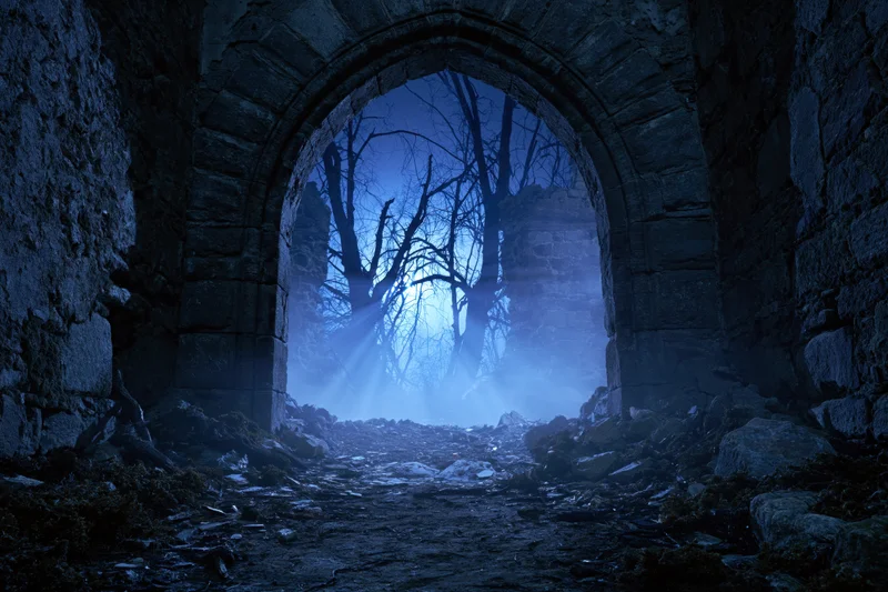 Stone ruin doorway at night with moonlight rays piercing through bare trees in foggy forest