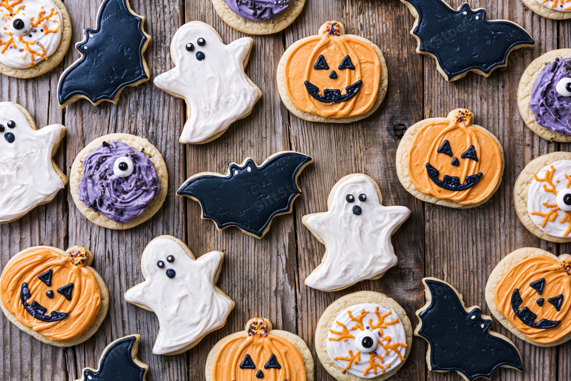 Assorted halloween sugar cookies decorated with royal icing arranged on wooden surface