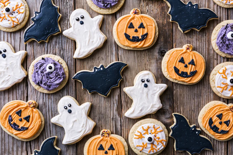 Assorted halloween sugar cookies decorated with royal icing arranged on wooden surface