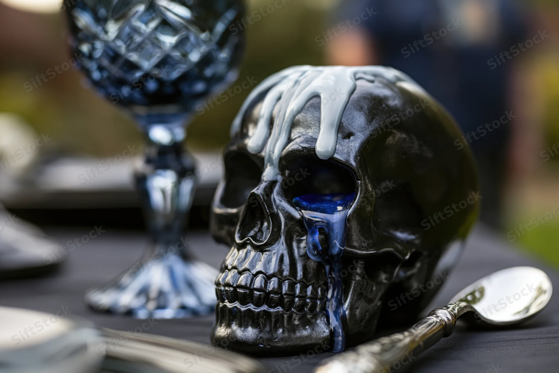 Black ceramic skull with melted white wax dripping on a dark table at a gothic dinner party