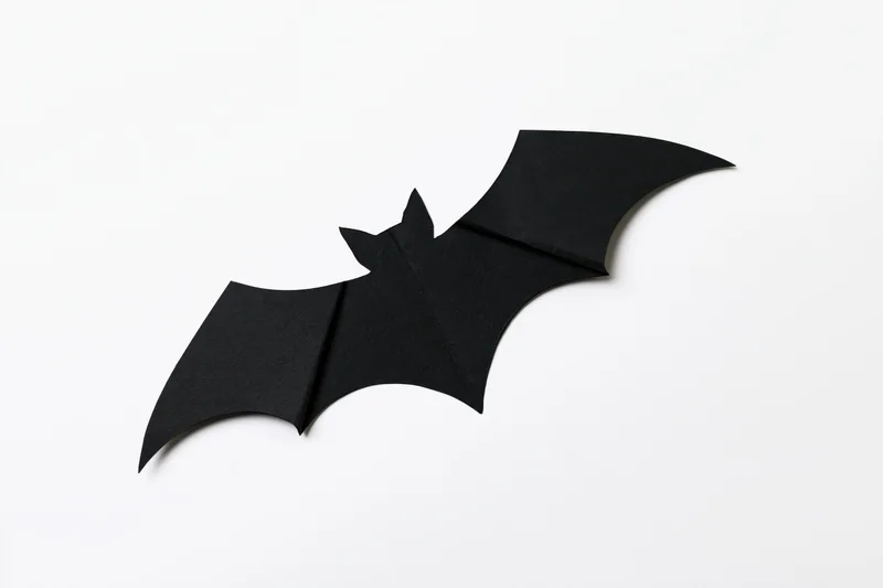 Black paper bat cutout with folded wings isolated on white background