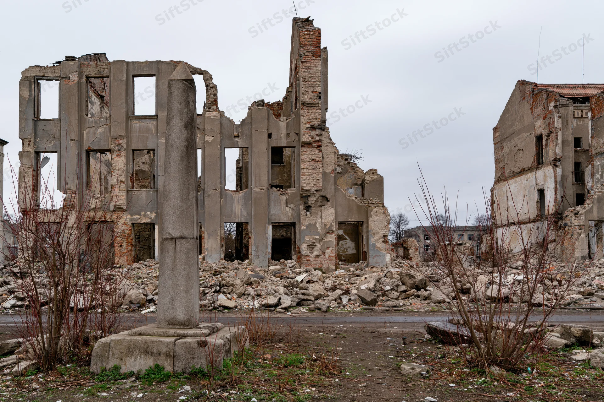 Bombed-out city block with crumbling concrete ruins and rubble under overcast sky