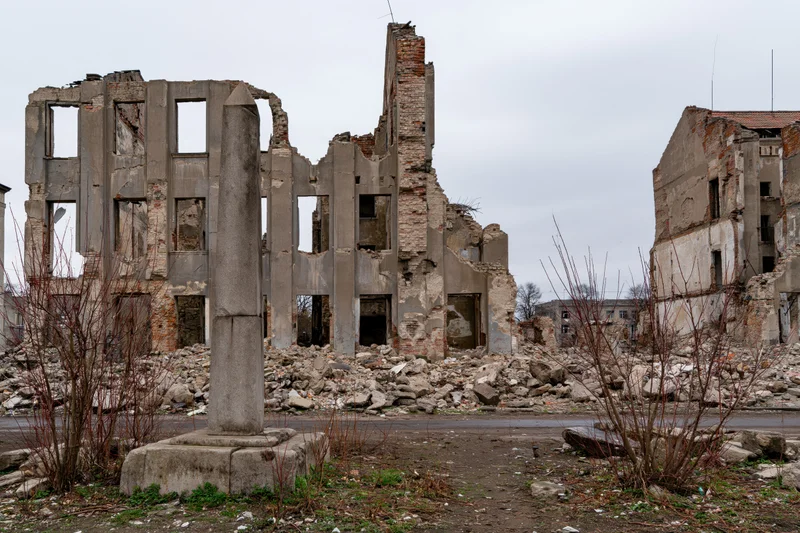 Bombed-out city block with crumbling concrete ruins and rubble under overcast sky