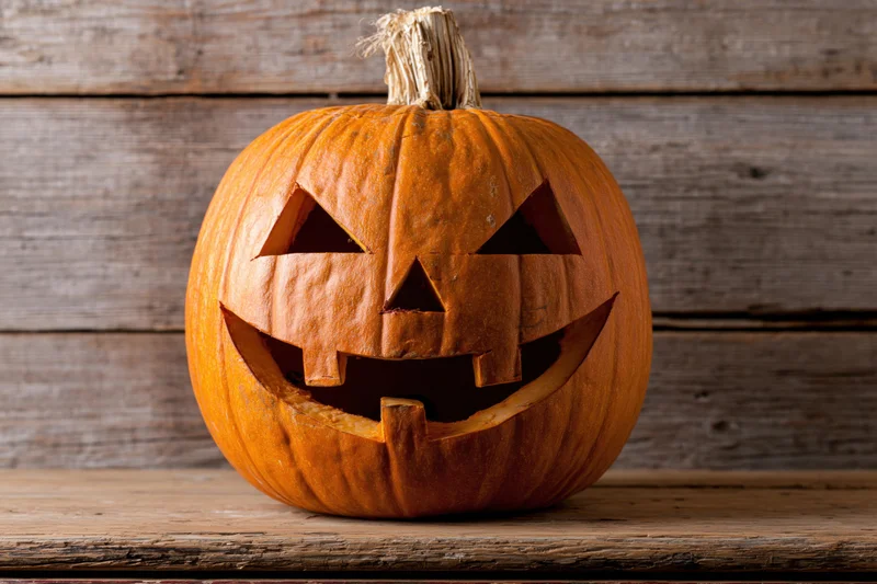Carved pumpkin with grinning face on wooden surface
