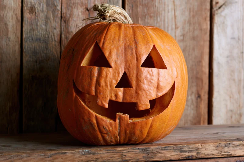Carved pumpkin with grinning face on wooden surface