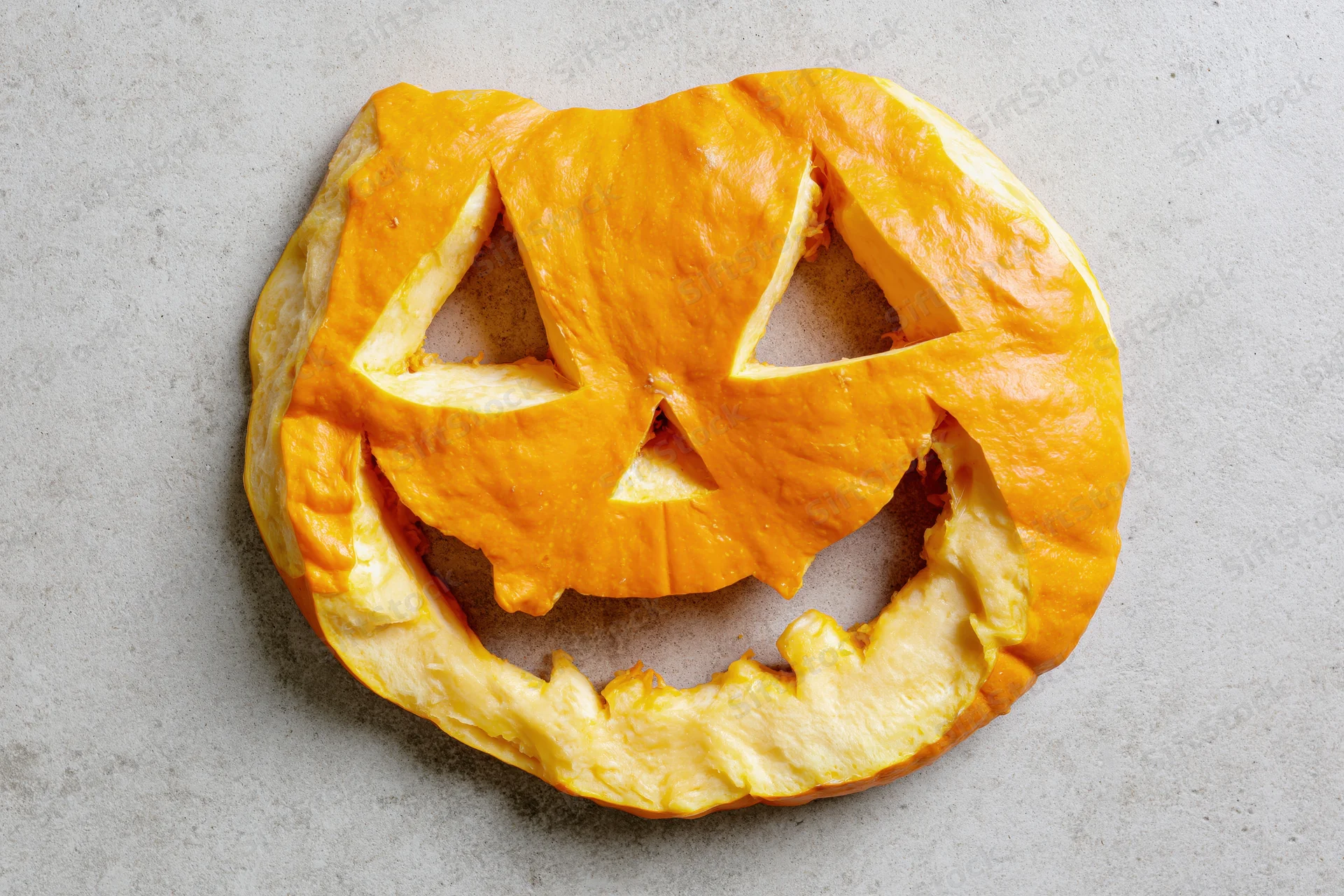 Carved pumpkin pastry arranged flat on a light grey surface