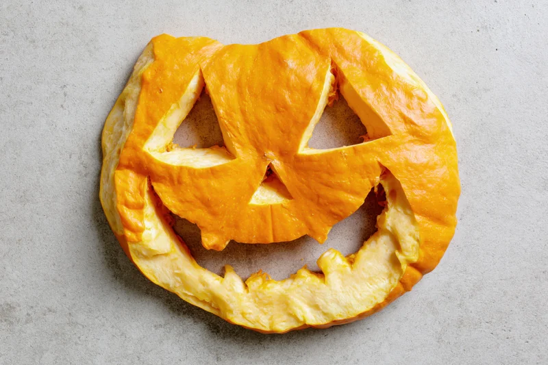 Carved pumpkin pastry arranged flat on a light grey surface