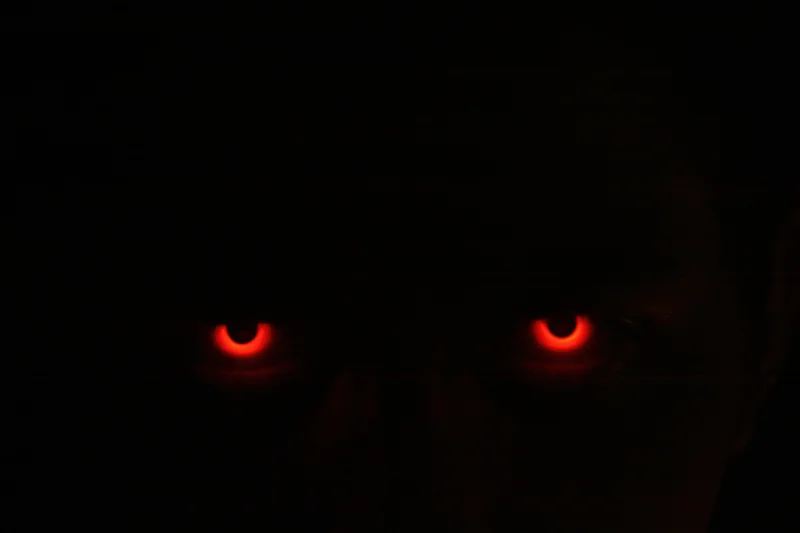 Glowing red eyes staring from complete darkness