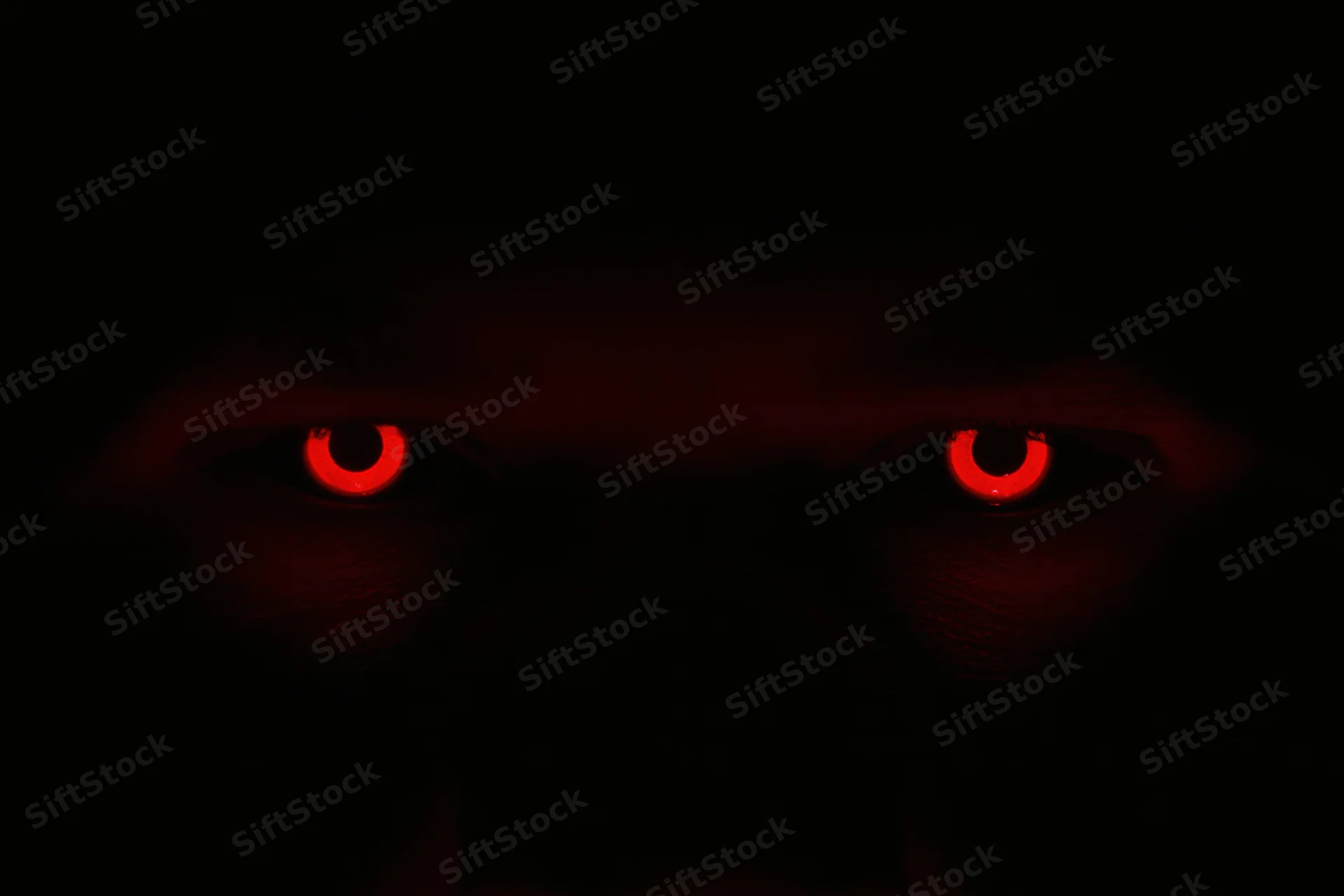 Glowing red eyes staring from complete darkness
