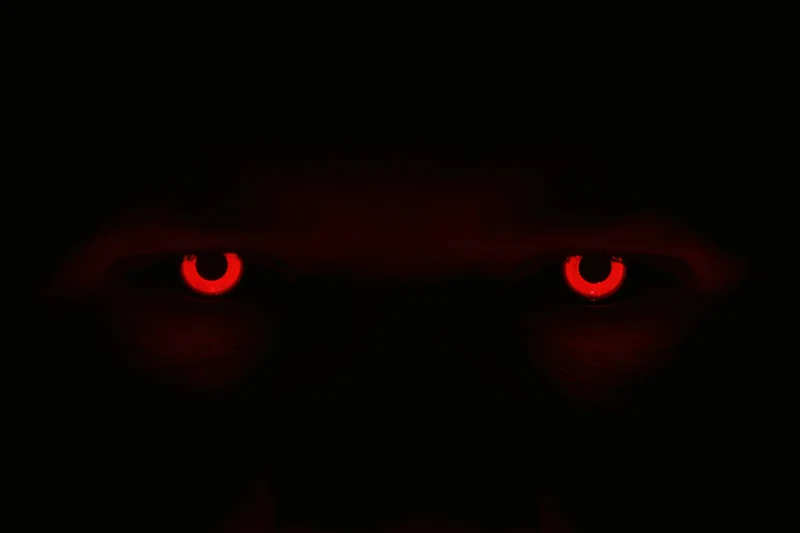 Glowing red eyes staring from complete darkness
