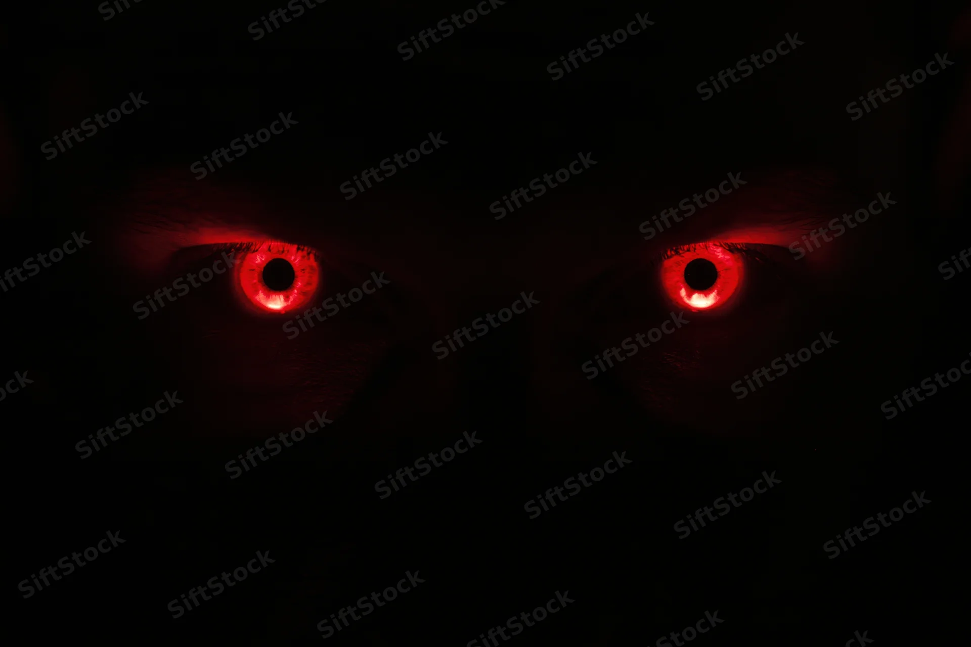 Glowing red eyes staring from complete darkness