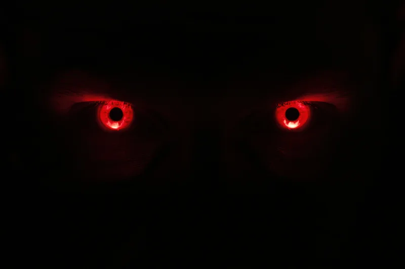 Glowing red eyes staring from complete darkness