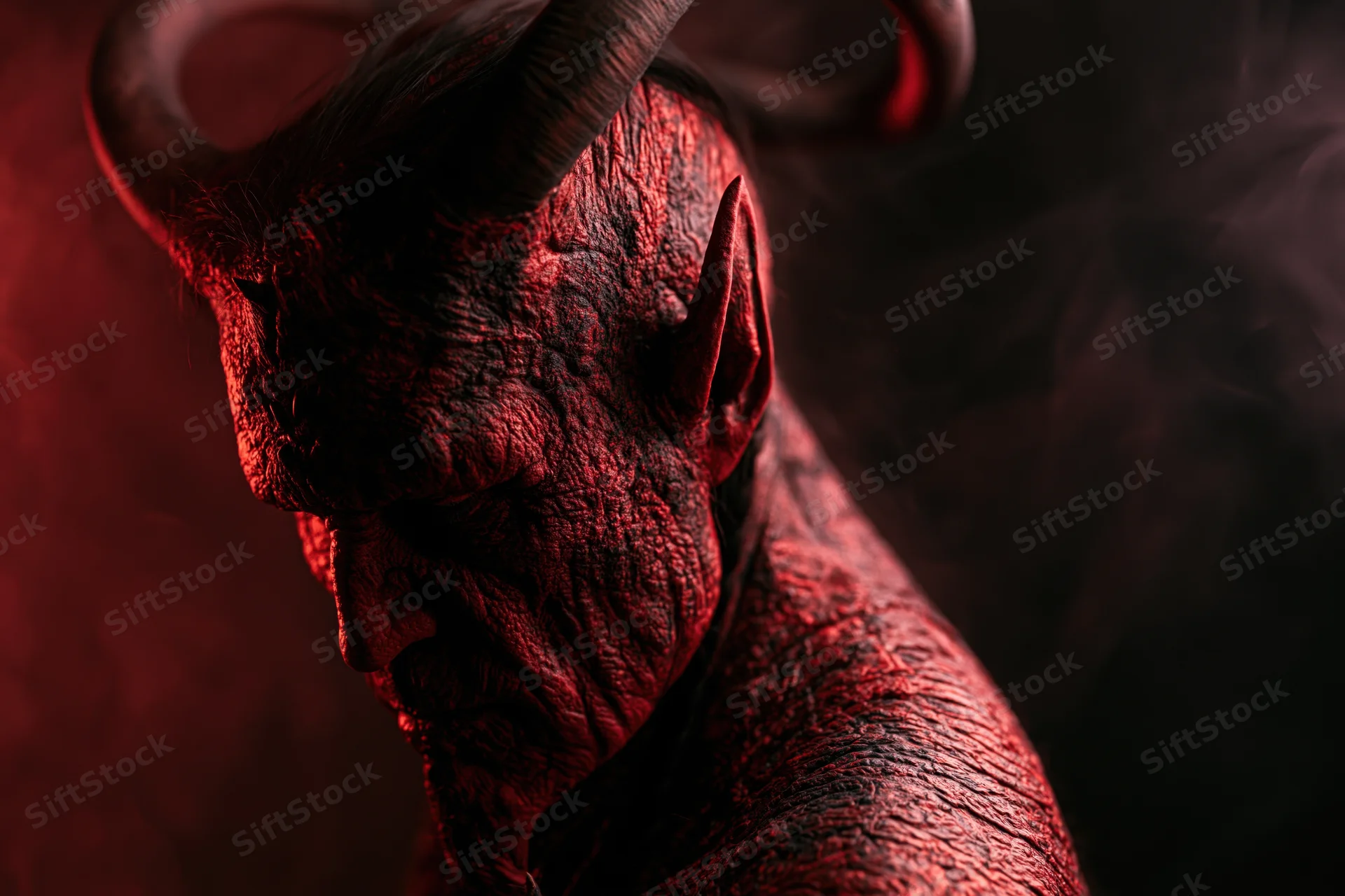Close-up profile of a demon with textured red skin and horns in a dark smoky setting