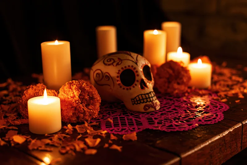 Decorated altar with painted skull, candles and marigolds on dark wooden table